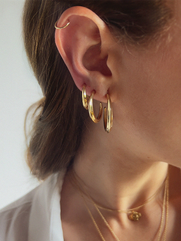 close up of model wearing 3 hoops in her lobe. The hoops are three different sizes. Large hoop is 1 inch and a half, middle hoops is 1 inch and the smallest hoop is three quarters of an inch.